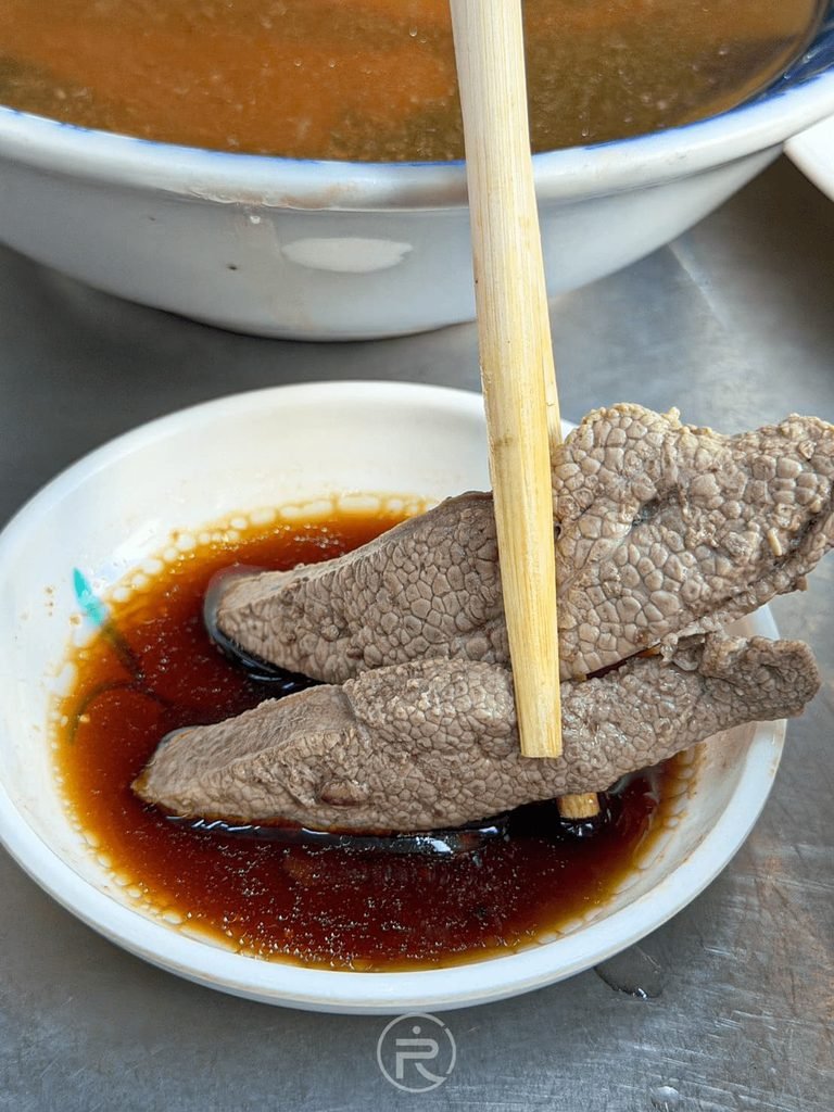 [筷夾豬肝沾醬]： 筷子夾起新鮮粉嫩的豬肝切片沾取特調蒜蓉醬油膏。
