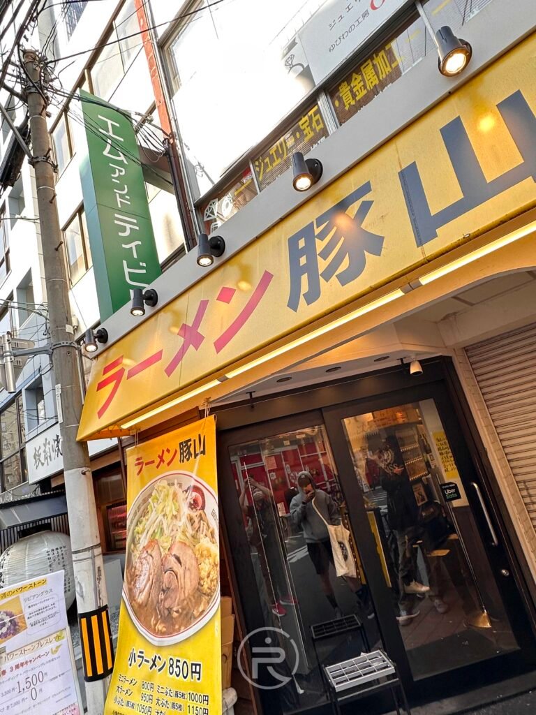 大阪南船場ラーメン豚山店門口，鮮豔的黃色招牌在街道中非常醒目。