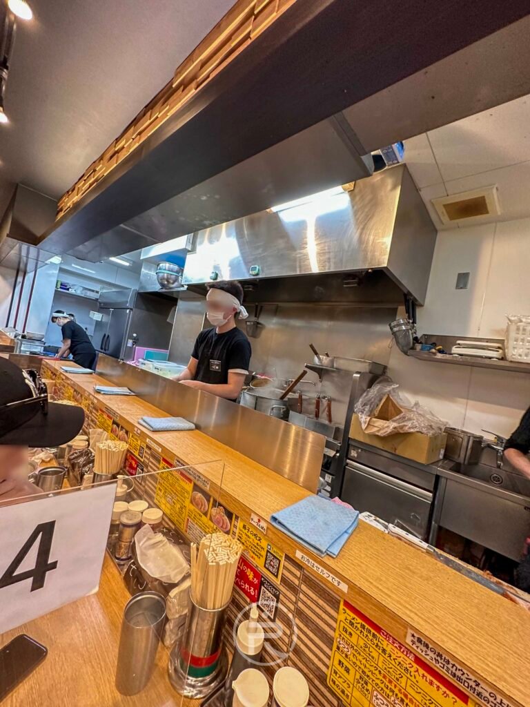 整潔的開放式廚房與用餐桌面，充滿日式拉麵店的職人氛圍。