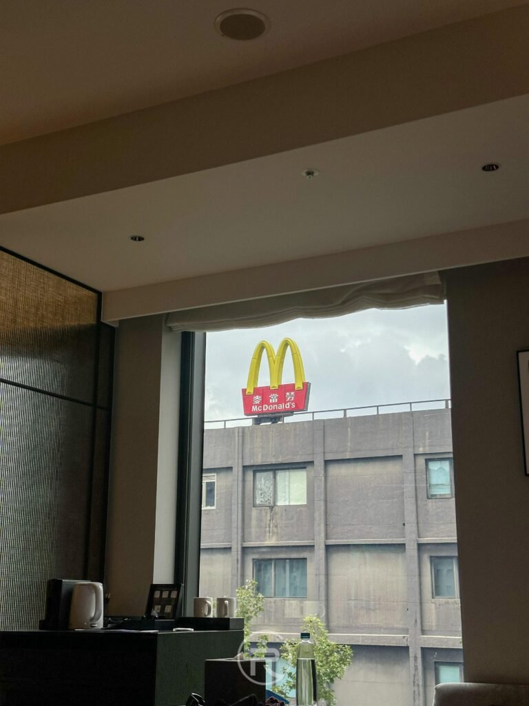 客房玻璃印有時代寓所標誌與窗外麥當勞街景的有趣視角。