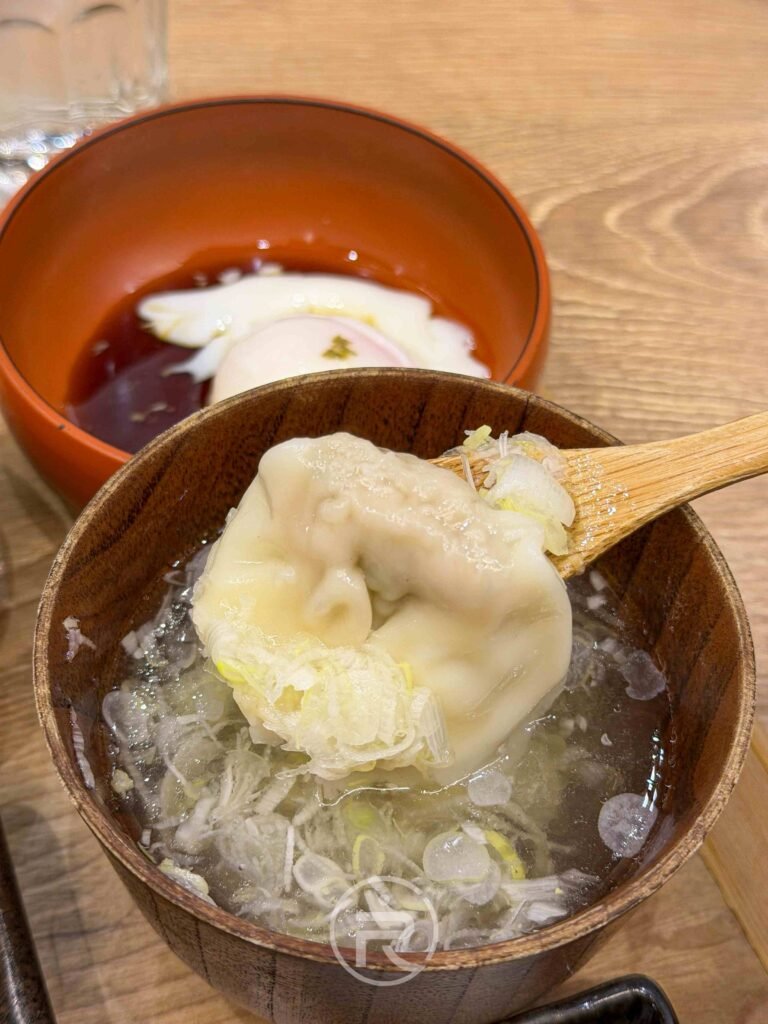 將湯裡的餃子放入湯匙中，準備感受咬下後瞬間噴發的濃郁肉汁。