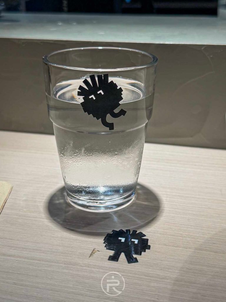 庵仁真店內簡約質感的玻璃水杯，印有品牌 LOGO 展現細節美學。