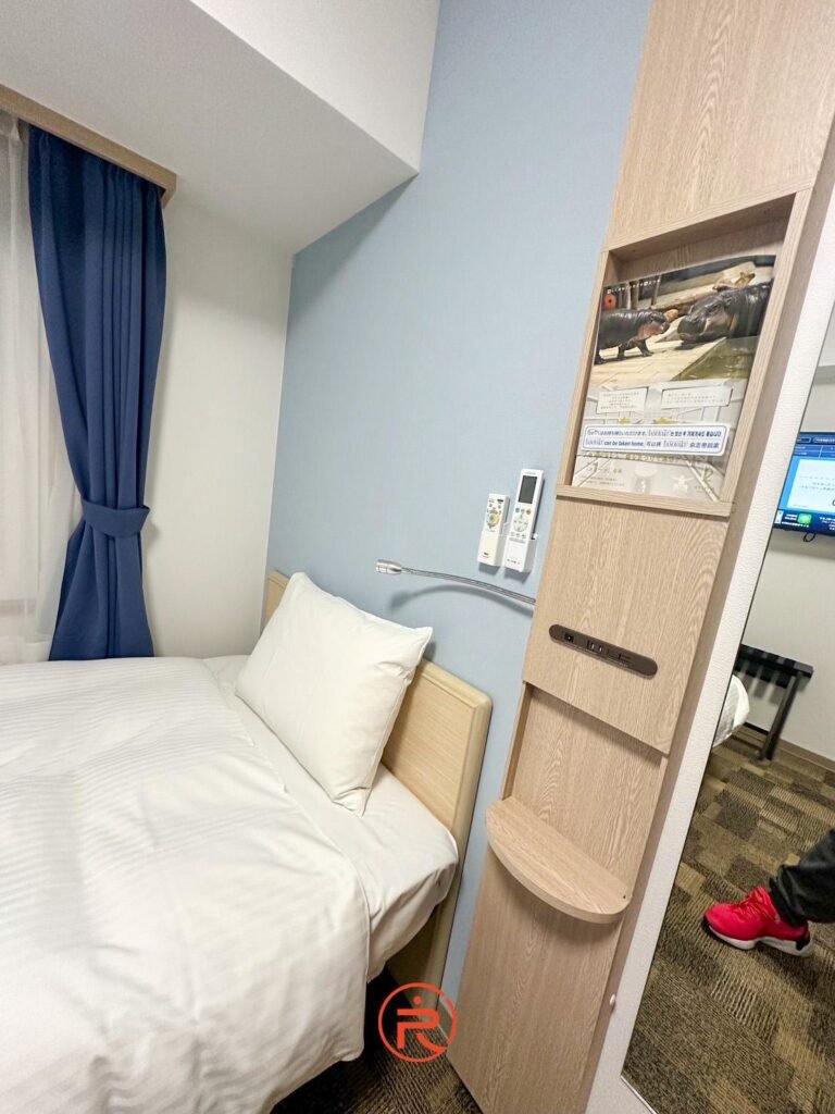 (床頭細節)東橫Inn客房床頭設施，包含閱讀燈、遙控器與多功能置物櫃