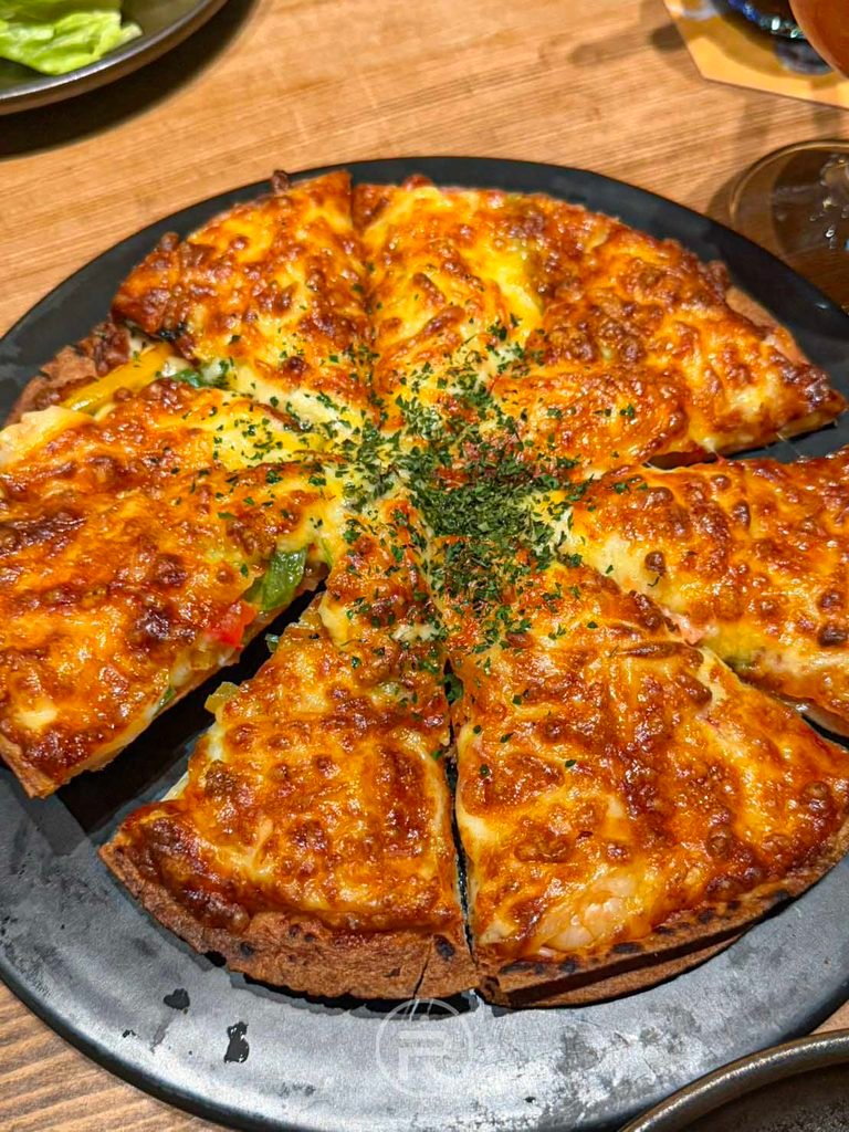 金色三麥 厚實的現烤蝦仁鮭魚披薩，邊緣微焦酥脆，用料飽滿