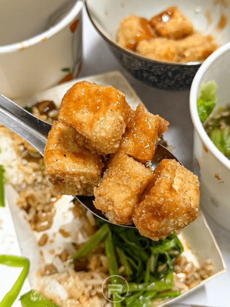 湯匙舀起外皮金黃焦脆的現炸豆腐塊,搭配豐原友家麵食便當享用。