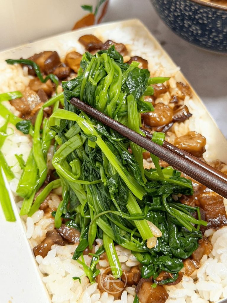 筷子夾起滷肉飯盒內附贈的現燙空心菜,青翠爽口去油解膩。