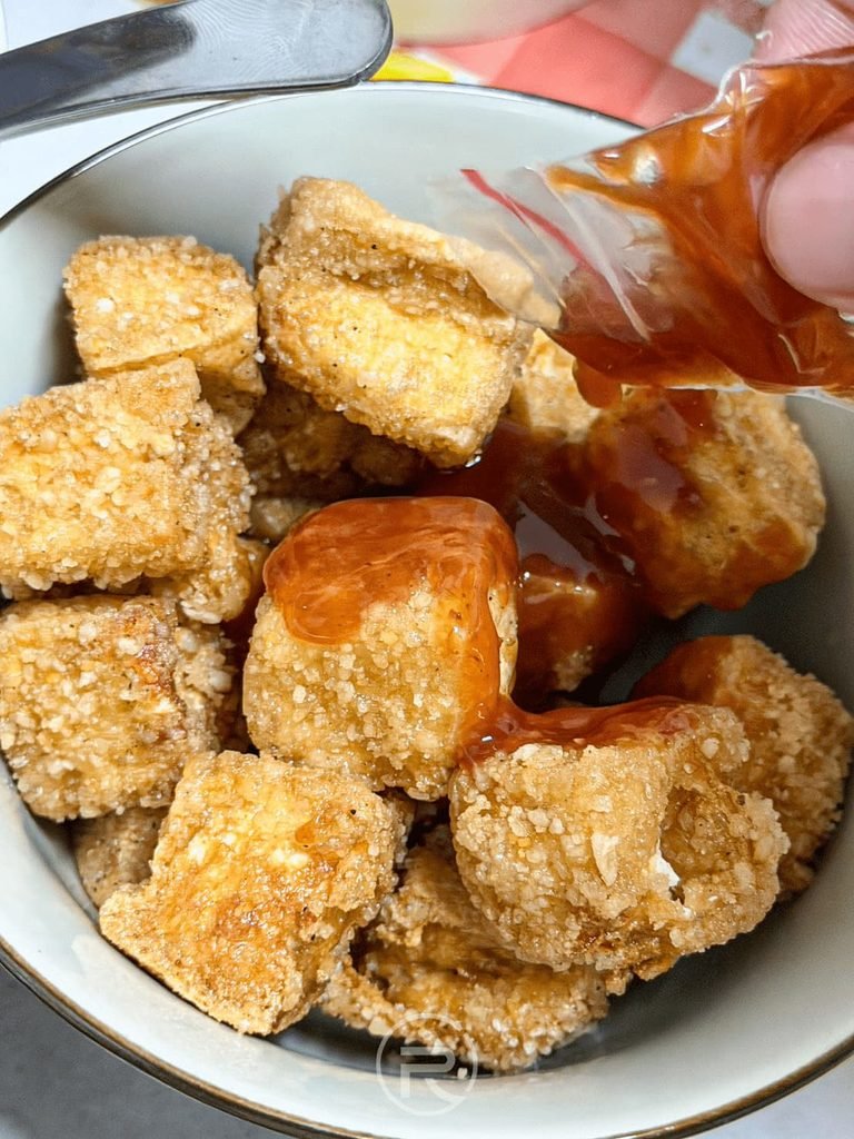 往炸豆腐碗中擠入店家附贈的經典甜辣醬汁提味。