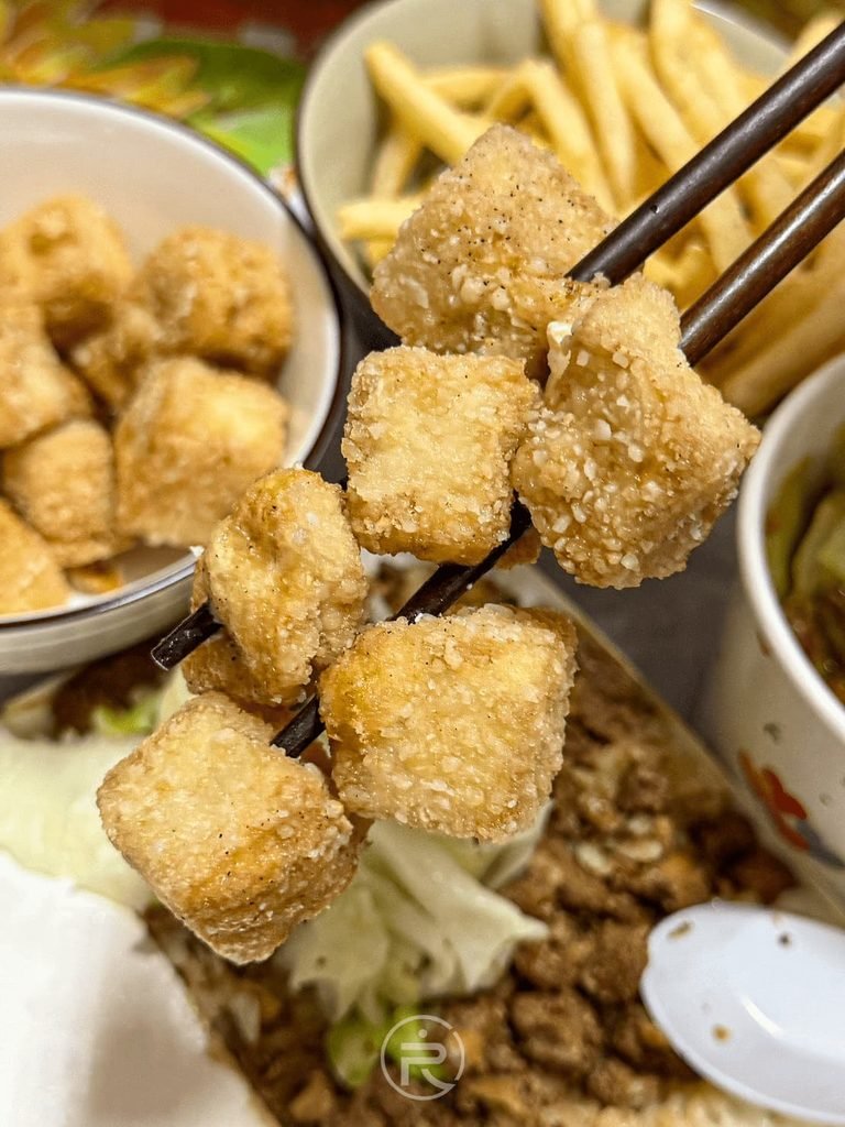  [筷夾雙塊炸豆腐]： 筷子一次夾起兩顆燙口炸豆腐，展現外酥內嫩的質地。