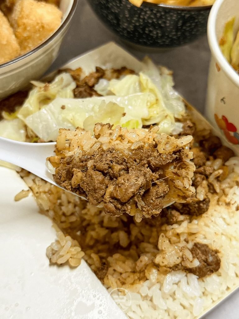 [肉燥飯大口吃]： 湯匙舀起大份量肉燥拌飯，展現豐原平價小吃的飽足感。