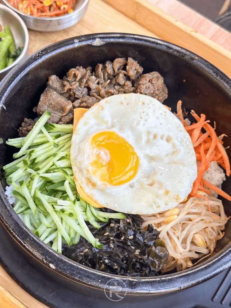  [石鍋拌飯特寫]： 「起士牛肉石鍋拌飯」豐富配料：特選牛肉、煎蛋、起司片、小黃瓜絲、胡蘿蔔絲與海苔絲。