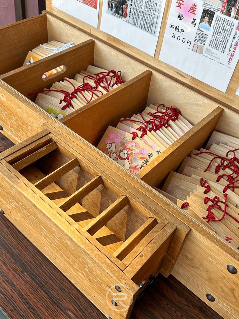 [御守與神籤木盒]： 社務所擺放整齊的木質抽屜，盛裝著各式祈願御守與神籤。