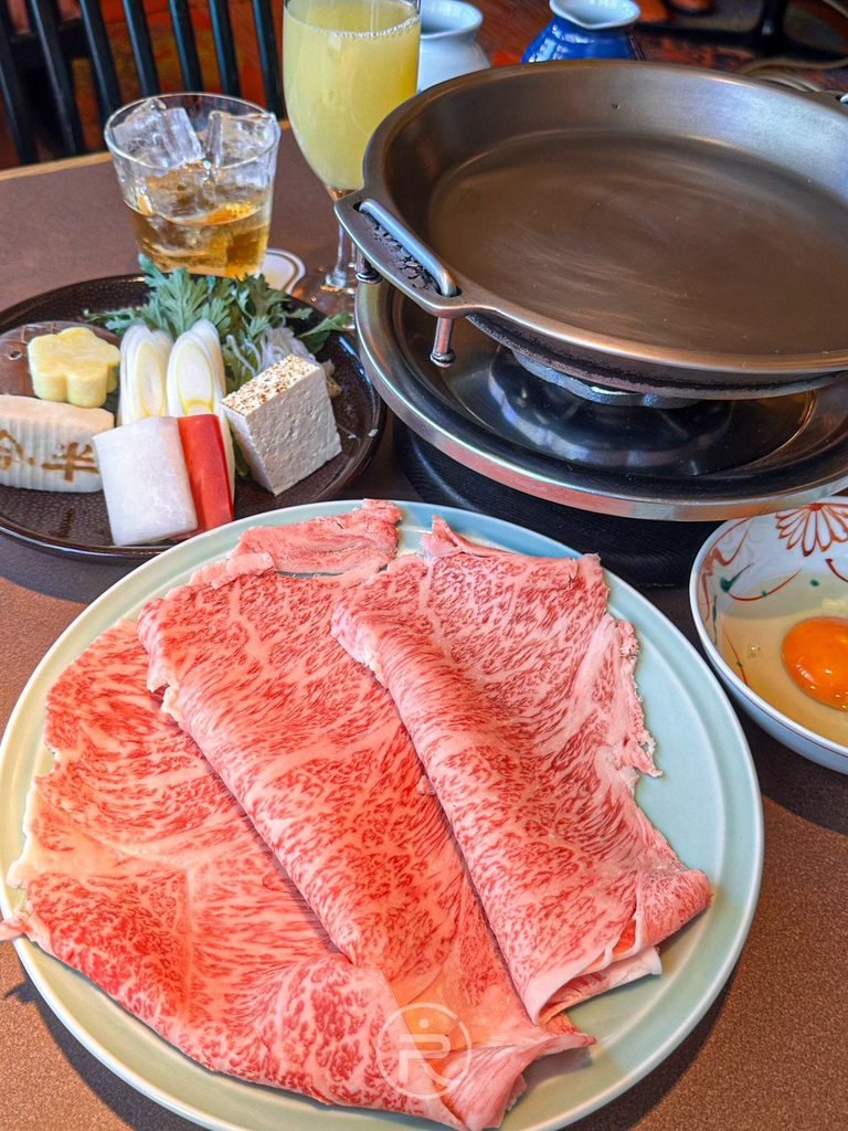  [全餐開席]： 今半萬窯壽喜燒定食全貌：頂級黑毛和牛肉盤、時蔬配料盤與生蛋。
