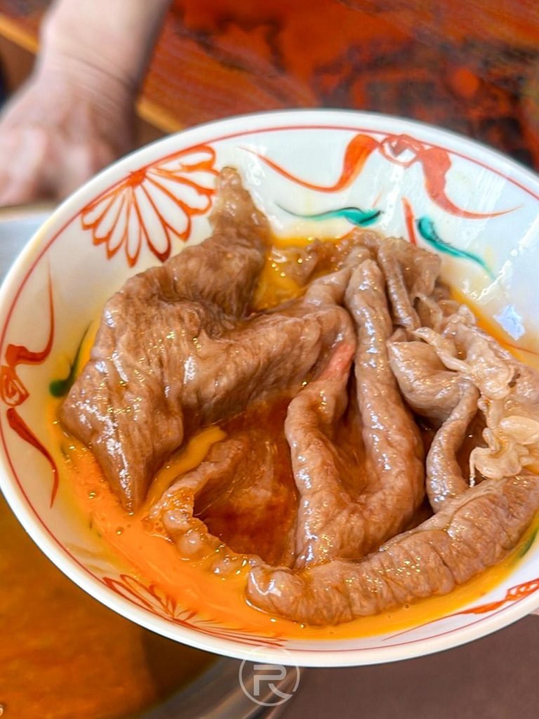  [裹蛋液和牛]： 剛起鍋的熱騰騰和牛肉片，迅速裹滿滑潤生蛋液盛入彩繪碗中。