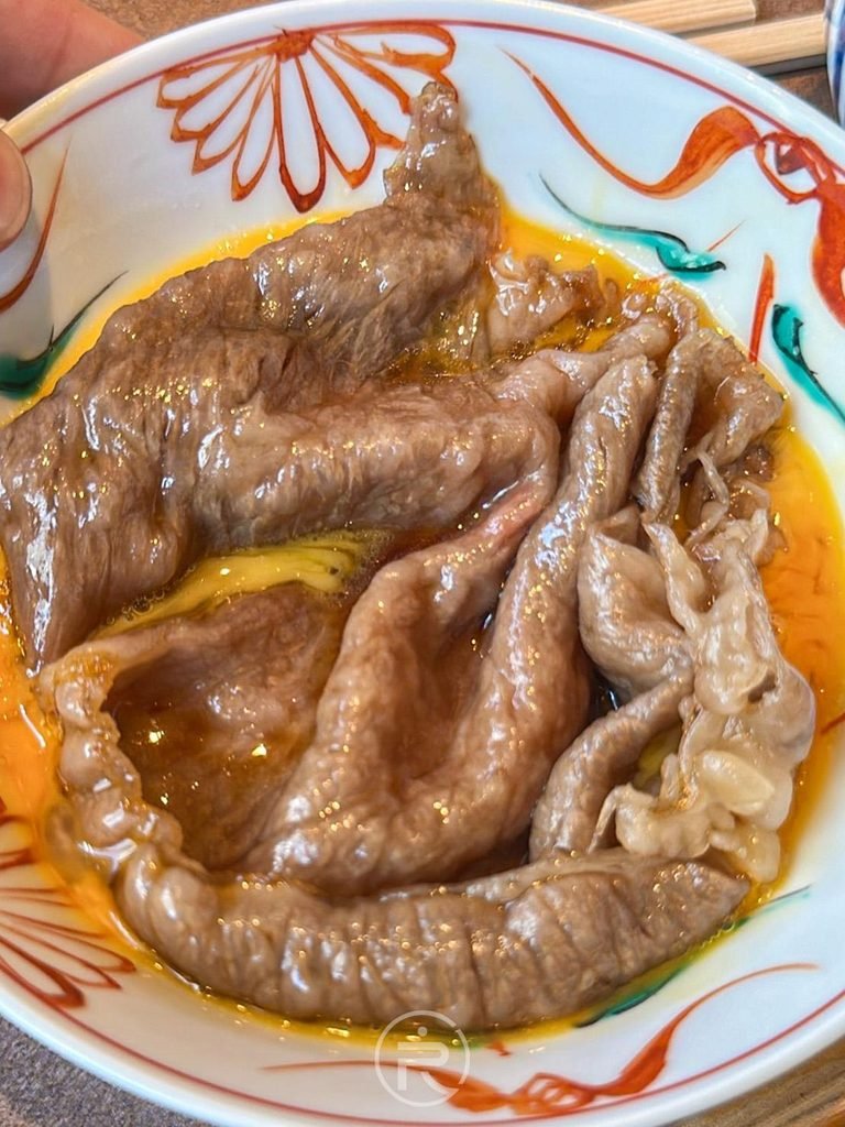  [和牛肉質特寫]： 沾附金黃蛋液的和牛肉片近拍，軟嫩多汁入口即化。