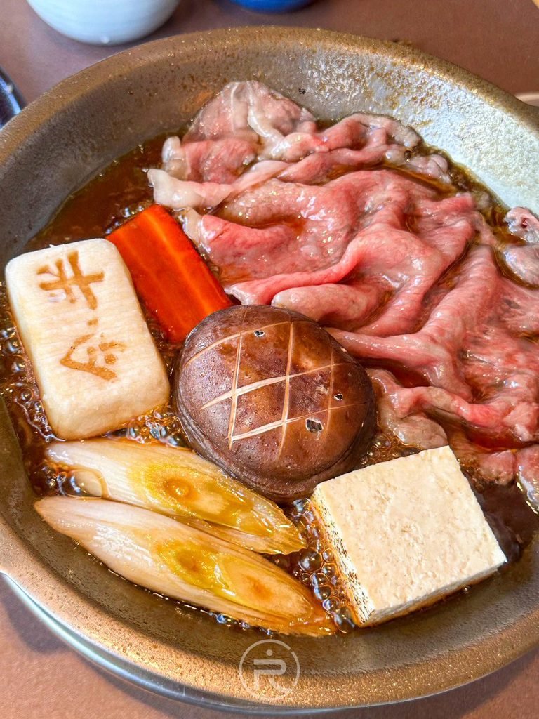  [鍋物煨煮全景]： 鍋中同時煨煮十字雕花香菇、和牛肉片、白蔥與烤豆腐。