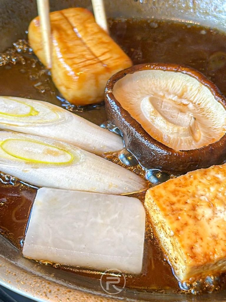  [時蔬煨煮特寫]： 滾燙割下醬汁中均勻吸收肉汁甜味的蒟蒻絲、大蔥與豆腐。