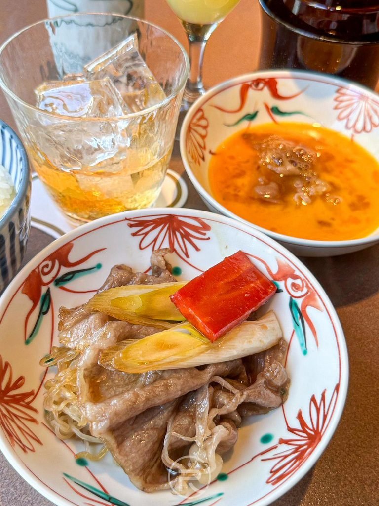  [時蔬配菜盤]： 盛裝煮熟時蔬、紅蘿蔔絲與牛蒡配菜的精緻陶瓷碟。