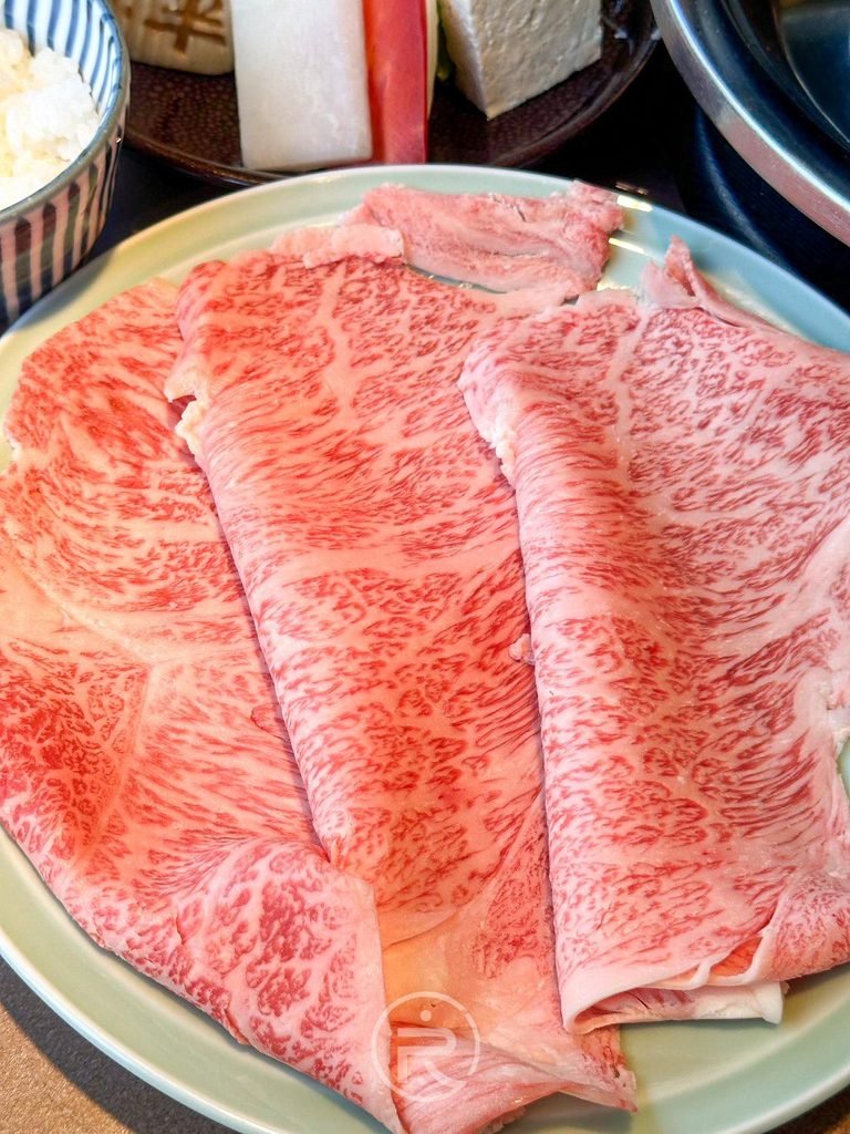  [油花和牛特寫]： 頂級黑毛和牛切片特寫，油花分布如大理石般細緻粉嫩。