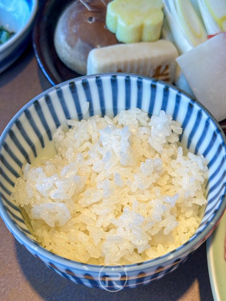  [香Q白飯]： 盛裝在藍白條紋瓷碗中的晶瑩剔透日本越光白米飯。