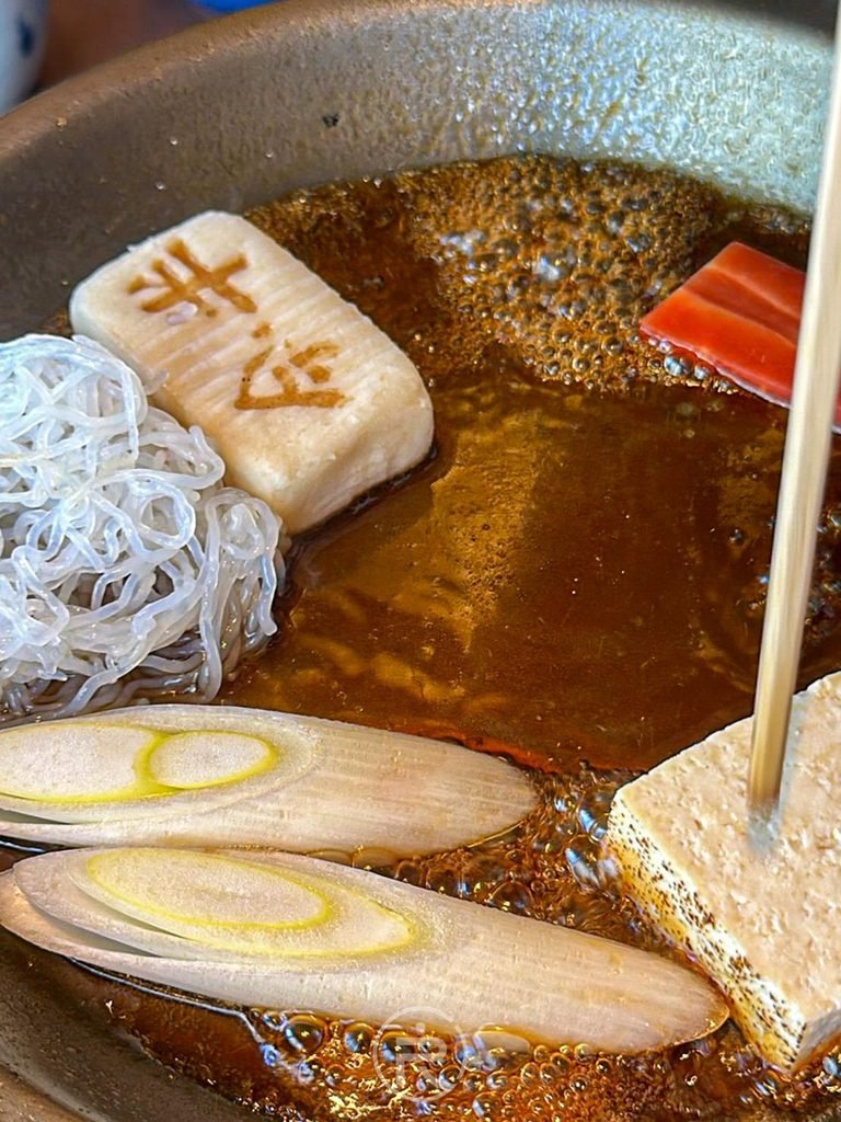 [先煮生麩蔬菜]： 醬汁滾沸後放入今半生麩、白蔥與烤豆腐慢慢煨煮入味。