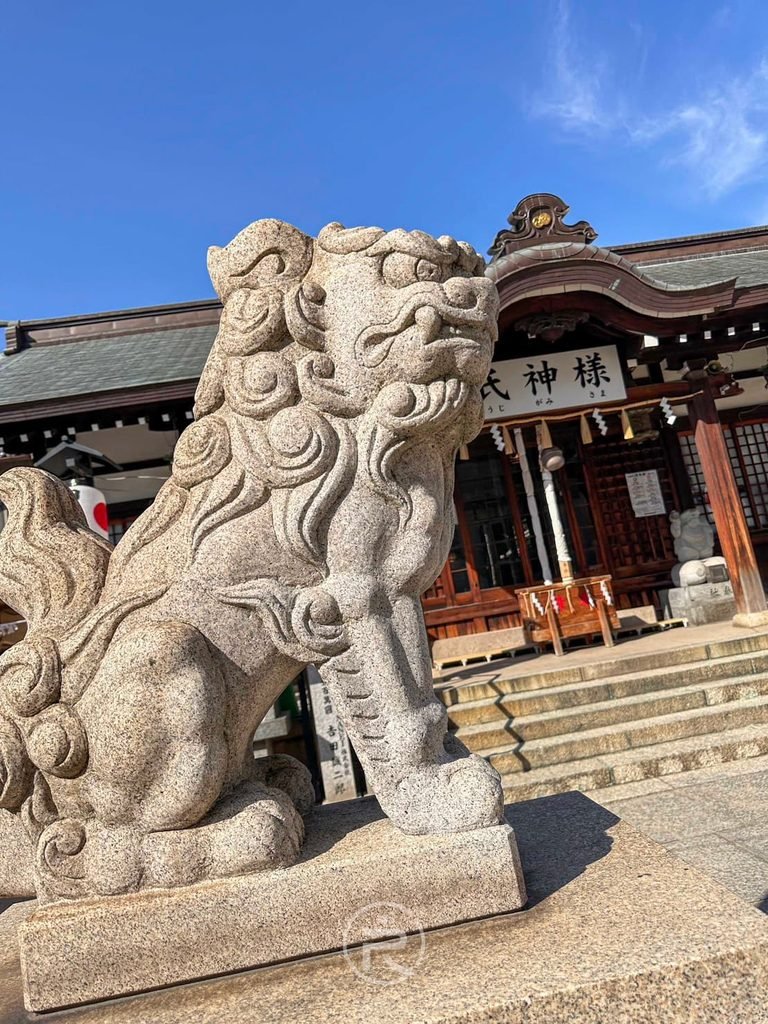 [石造狛犬特寫]： 守護在拜殿前的石造狛犬雕像特寫，神態威風莊嚴。