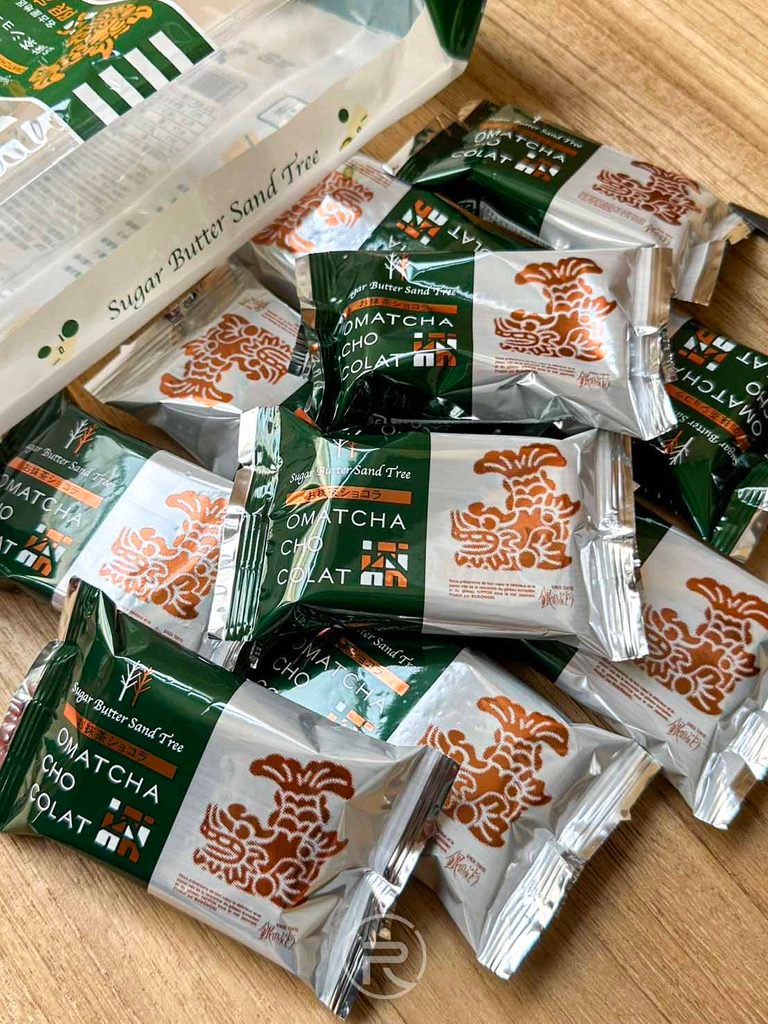 名古屋 [散裝餅乾大集合]： 木質桌面上陳列的大量散裝抹茶砂糖奶油樹餅乾，適合辦公室分送分享。