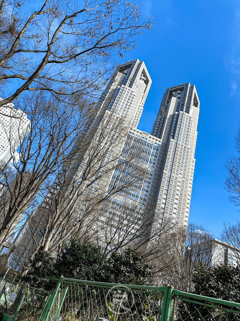  [仰望東京都廳雙塔]： 從熊野神社境內抬頭仰望，藍天下西新宿標誌性的東京都廳第一本廳舍摩天大樓。
