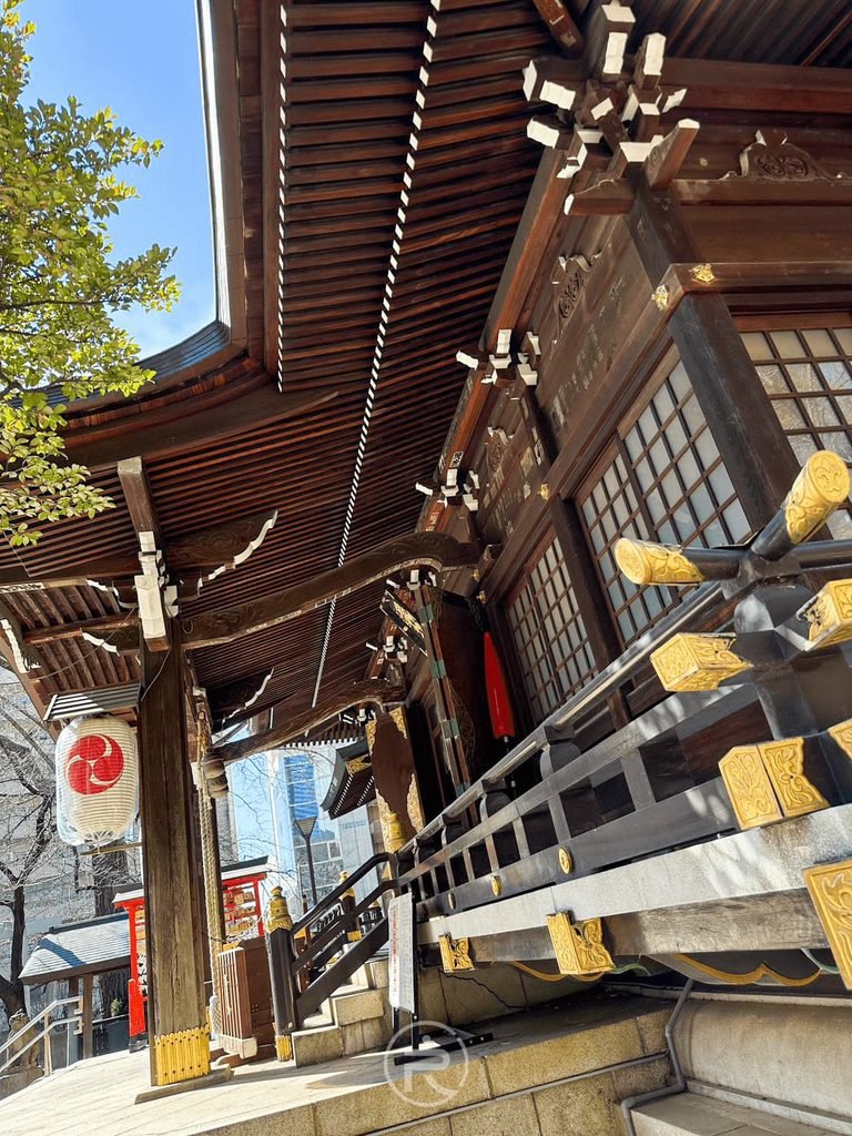[斗栱木雕特寫]： 仰拍本殿屋簷角落層層交錯的斗栱構造與金箔飾片細節。