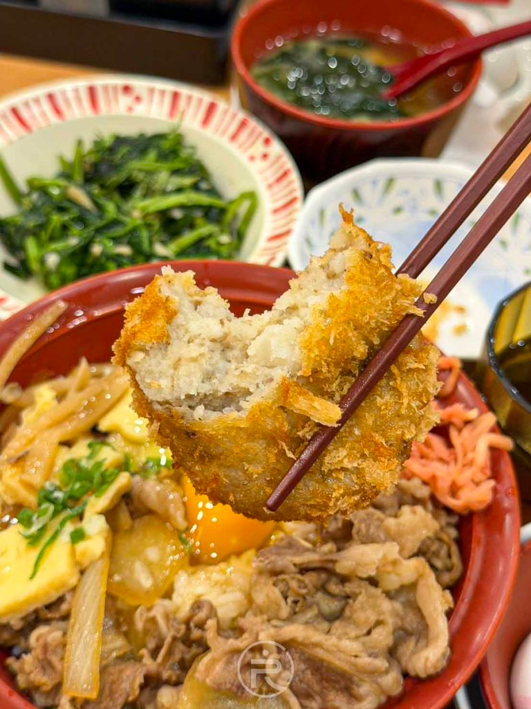 咬開可樂餅展現內部綿密香甜的牛肉馬鈴薯泥內餡斷面。