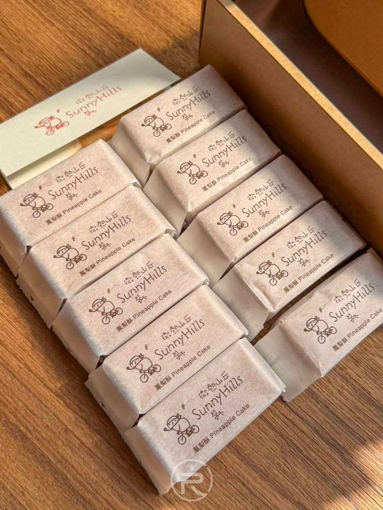  [整盒鳳梨酥俯拍]： 盒裝雙排整齊陳列的棉紙獨立包裝土鳳梨酥，送禮體面大方。