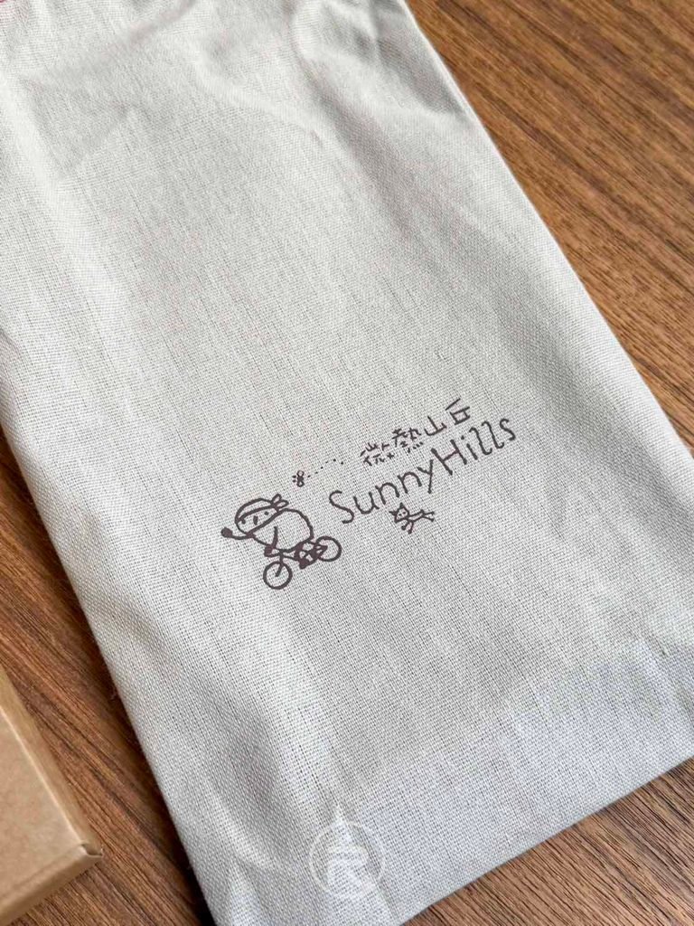 [品牌文字印花]： 麻布袋上的「微熱山丘 SunnyHills」經典手繪風品牌字樣。