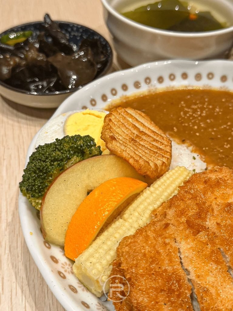  [豐富配菜特寫]： 咖哩盤邊附贈的豐富配料：蘋果片、薯格格、玉米筍、綠花椰與水煮蛋。