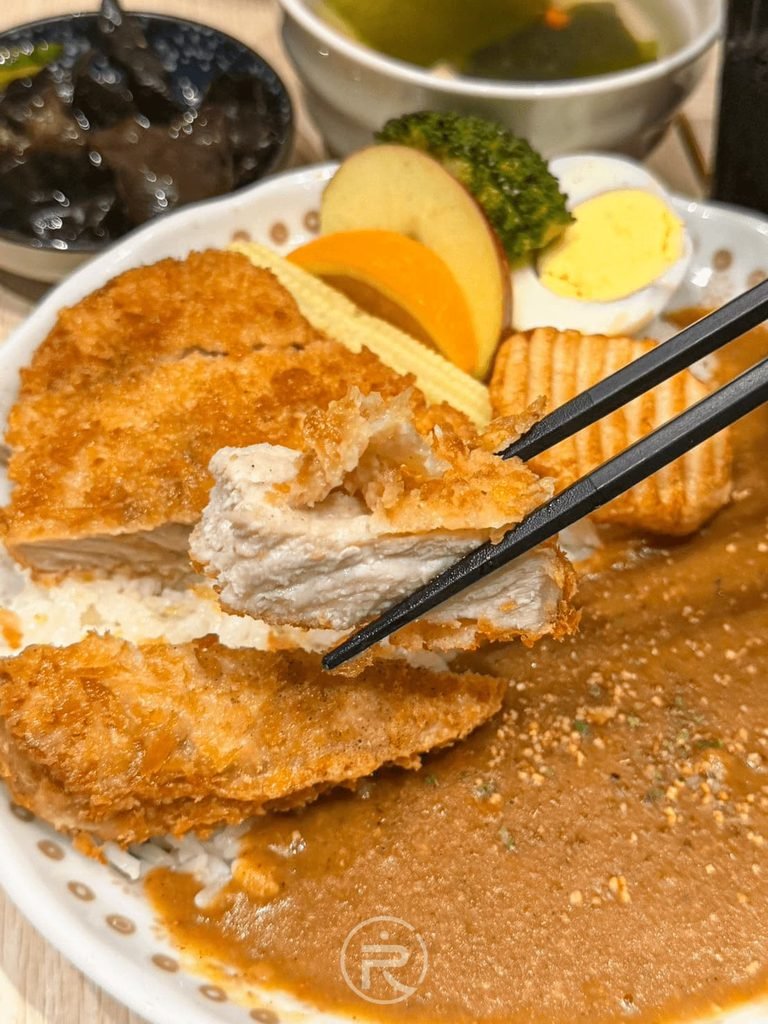  [夾起多汁豬排]： 筷子再次夾起外皮酥脆內裡厚嫩的炸豬排，台中平價咖哩推薦。