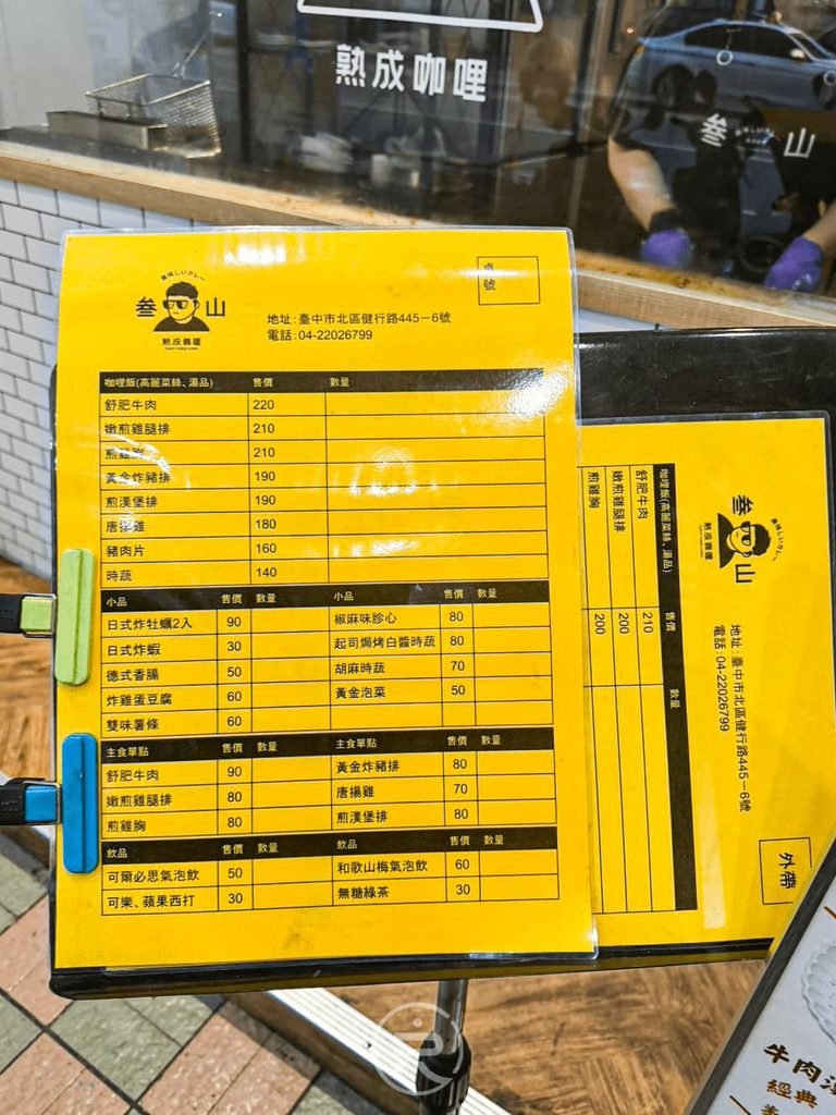 [黃色外帶菜單]： 門口擺放的鮮黃色詳細點餐單，清楚標示各款主餐、小菜與飲品價格。
