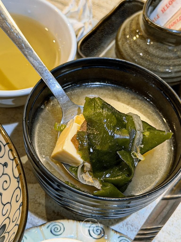  [湯匙舀海帶湯]： 竹野日式料理附贈的熱熱味噌湯，撈起滿滿嫩豆腐與海帶芽配料。