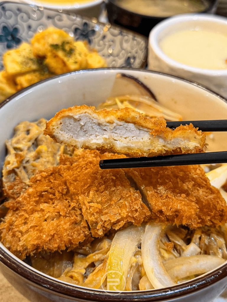  [豬排斷面厚度]： 筷子展示炸豬排扎實的肉質厚度斷面，不乾柴且保有肉汁。