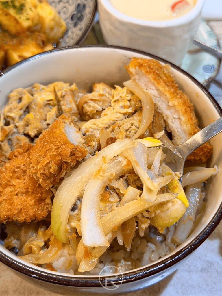 [半食美味碗底]： 用餐進行中的豬排蓋飯特寫，白飯均勻吸附甘甜壽喜燒醬汁。