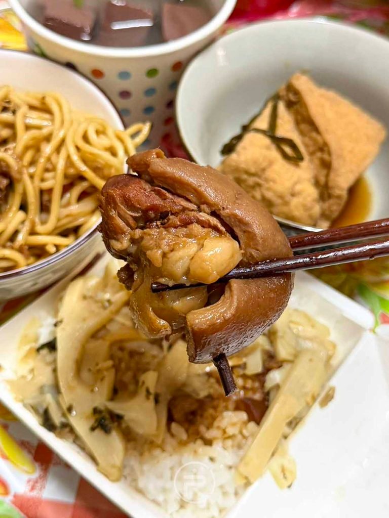  [夾起腳庫肉]： 用筷子夾起插著牙籤的厚實腳庫肉，膠質晶瑩飽滿。