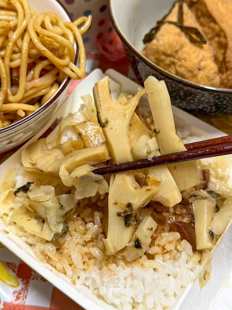  [夾起酸甜筍絲]： 筷子夾起鋪在飯上的滷筍絲，是去油解膩的絕佳配菜。