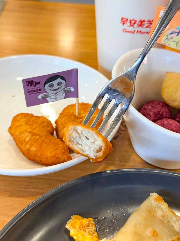  [叉子叉雞塊細節]： 叉起外酥內嫩的麥克雞塊，搭配聯名套餐的小點心。