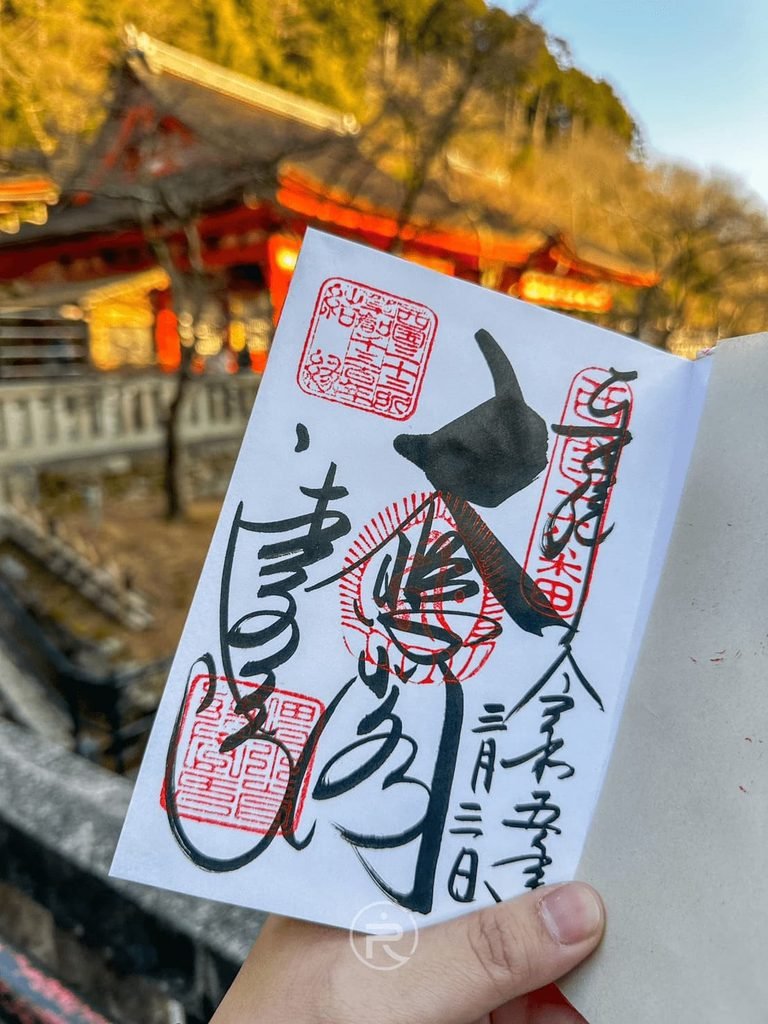  [手持大悲閣御朱印]： 手持京都清水寺手寫「大悲閣」御朱印，背景為夕陽映照下的朱紅寺殿