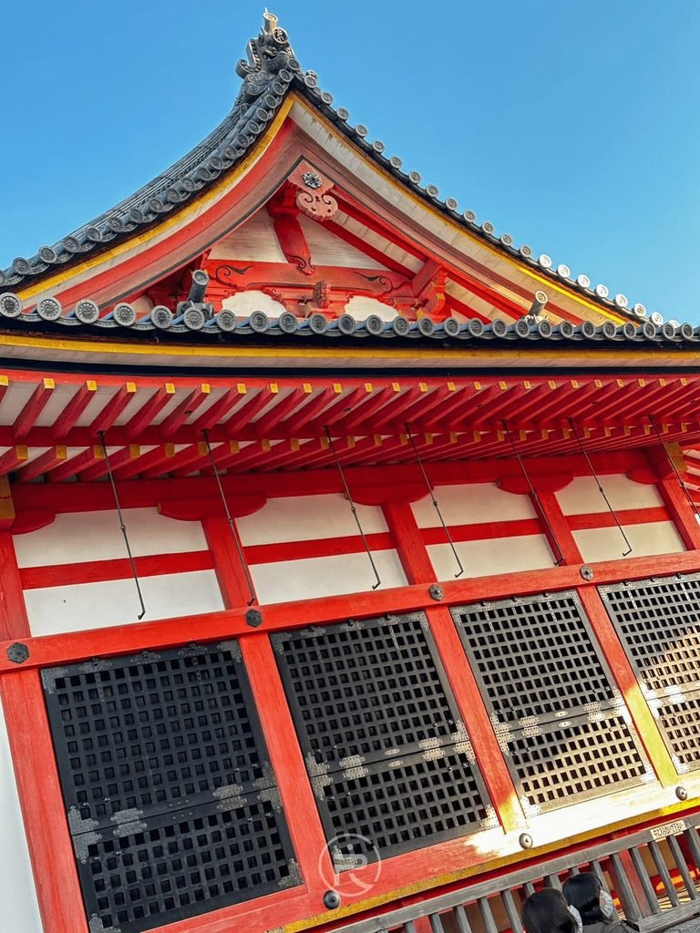 [朱紅堂宇建築細節]： 清水寺鮮豔朱紅色的日式木造堂宇屋簷與傳統白牆格子窗特寫。