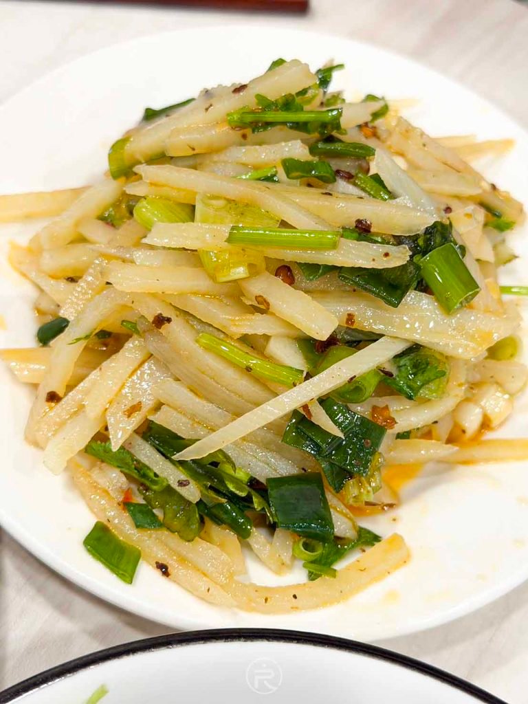  [川味脆薯絲特寫]： 涼拌川味脆薯絲近拍，刀工細緻搭配青蔥與後勁十足的麻辣紅油。