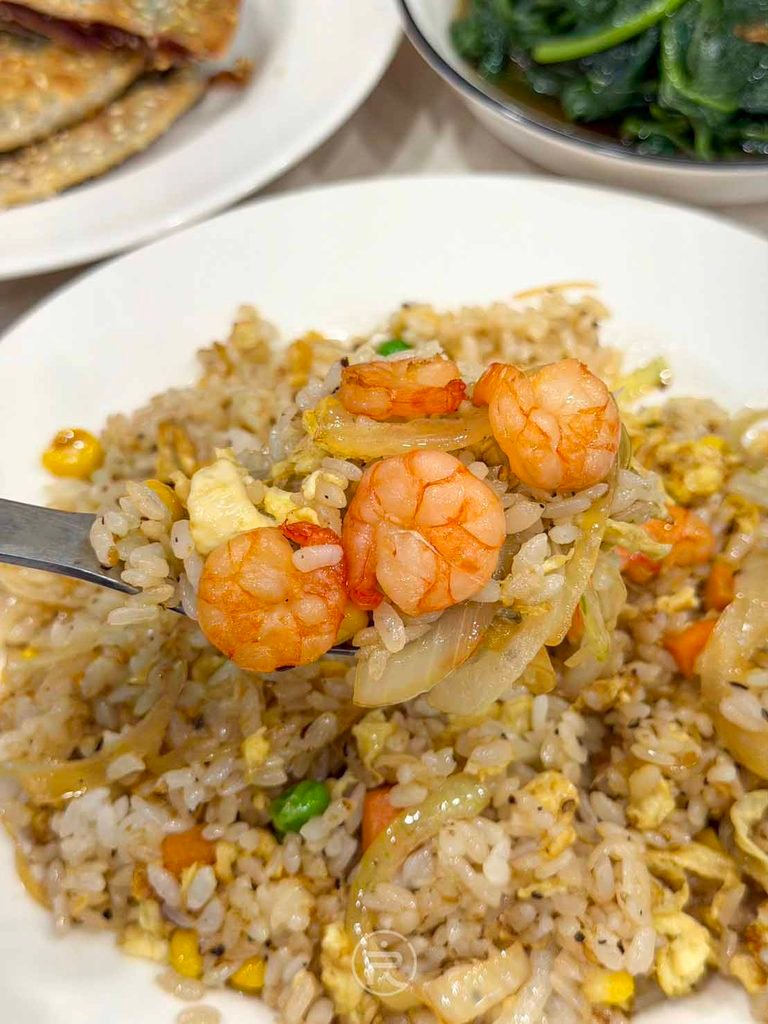 [大口吃蝦仁炒飯]： 湯匙盛著滿滿金黃炒飯與大蝦仁，展現家常手路菜的高水準。