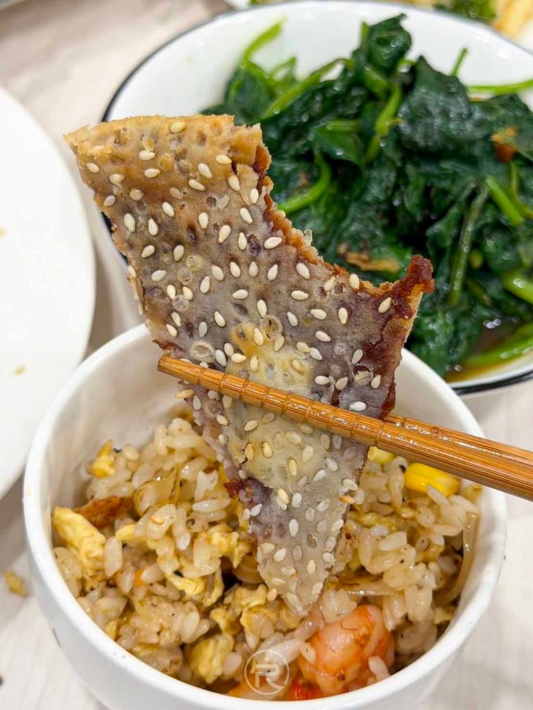 [鍋餅配炒飯視角]： 拿著芝麻鍋餅搭配炒飯用餐，鹹甜交替的道地小館滋味。
