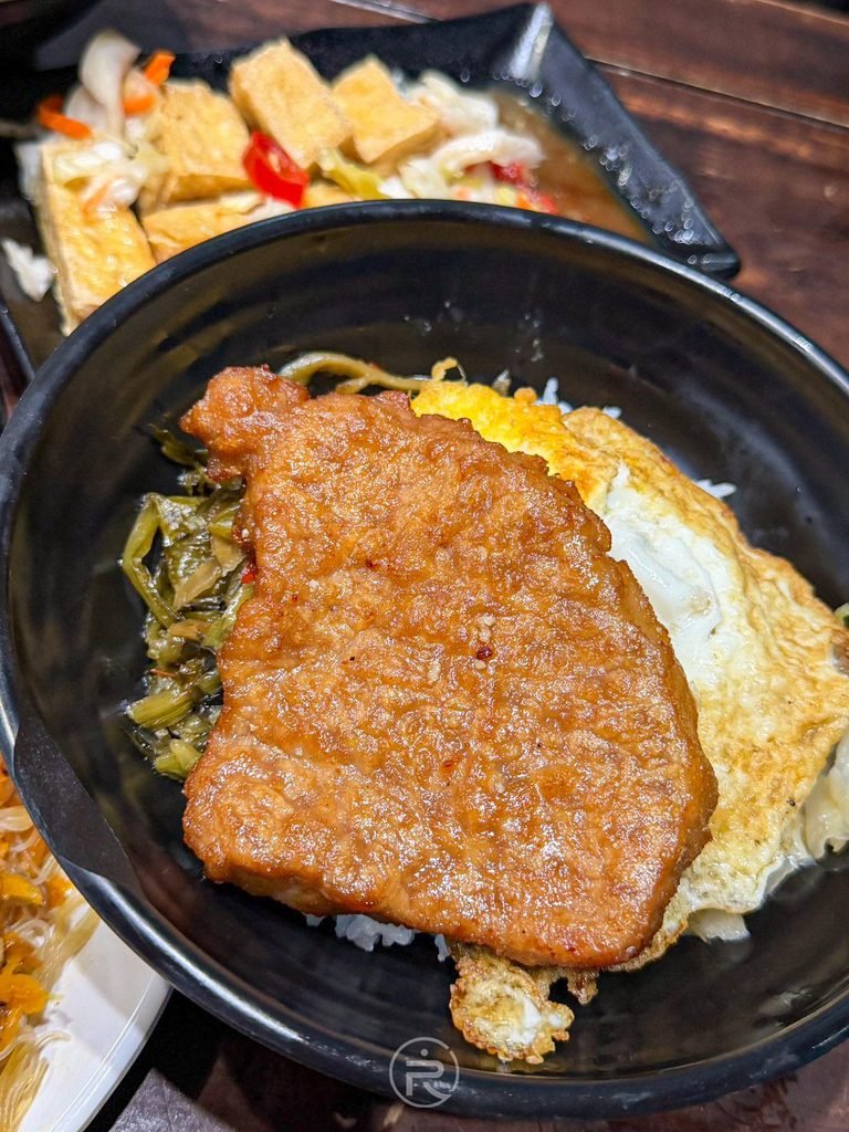 [燒肉飯黑碗俯拍]： 經典馬路益燒肉飯全視角，金黃肉排搭配酸菜荷包蛋的黃金三角組合。