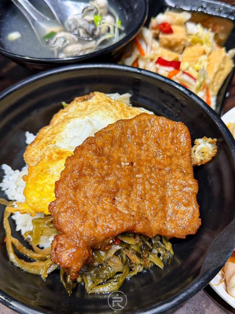 [燒肉飯配酸菜特寫]： 咬開一角的香酥燒肉排，搭配微酸爽口的酸菜最能去油解膩。