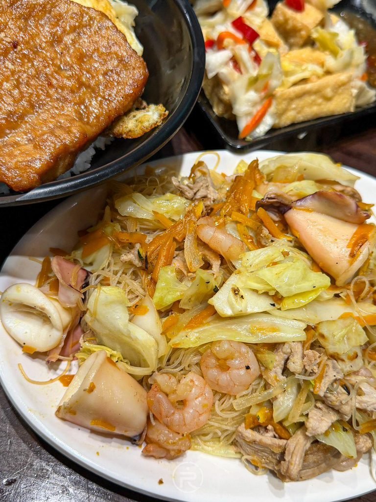[餐點排列視角]： 桌面擺放金瓜炒米粉與熱騰騰炸物，展現滿桌澎湃在地好味道。
