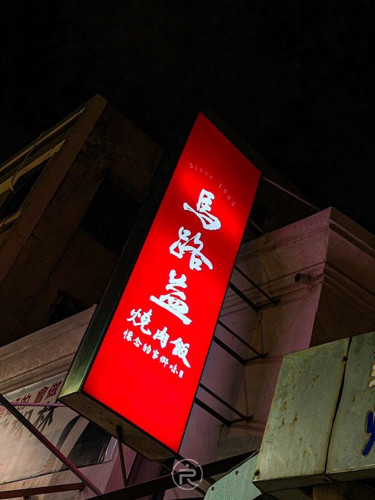 [夜間紅色立體招牌]： 馬路益燒肉飯夜間發光的亮紅色直立招牌，巷弄內的醒目指標。