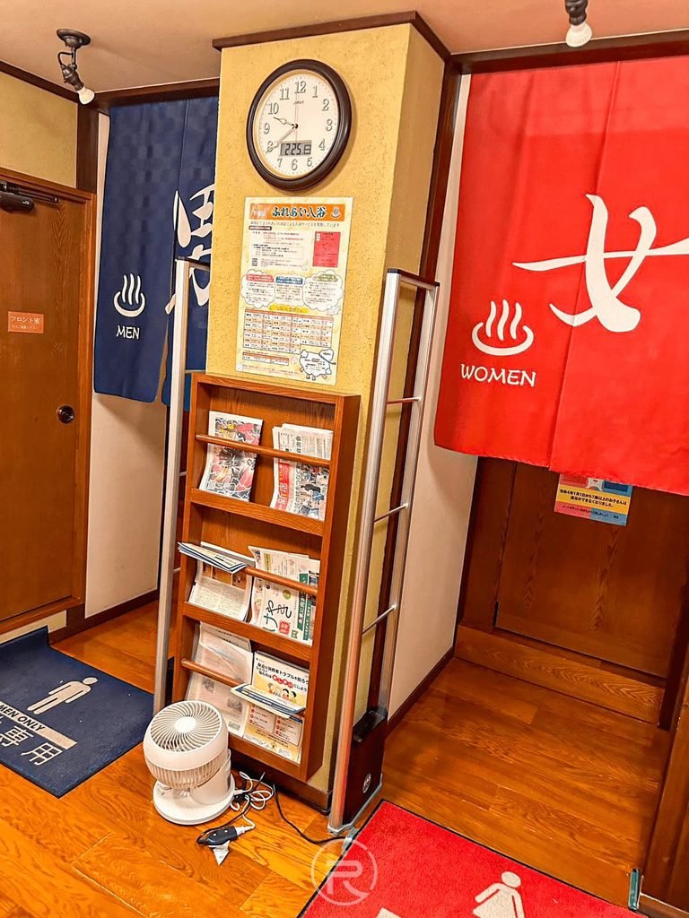 [男女湯入口廊道]： 浴場入口走廊，左側為深藍色「男湯」門簾、右側為鮮紅色「女湯」門簾。